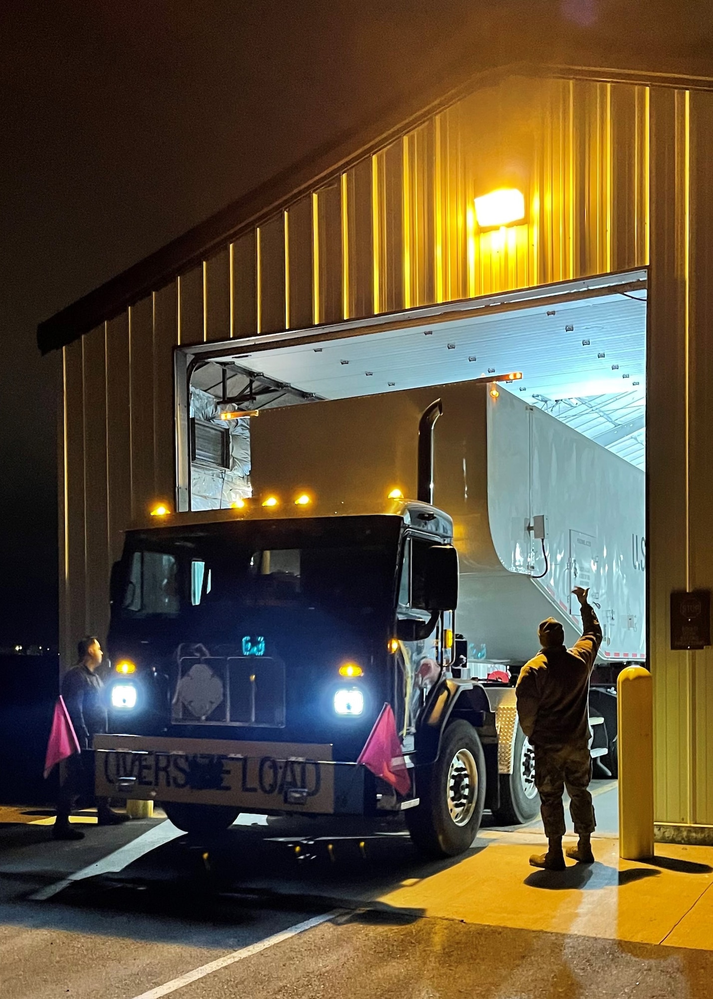 Two Airmen spot a third driving a truck.