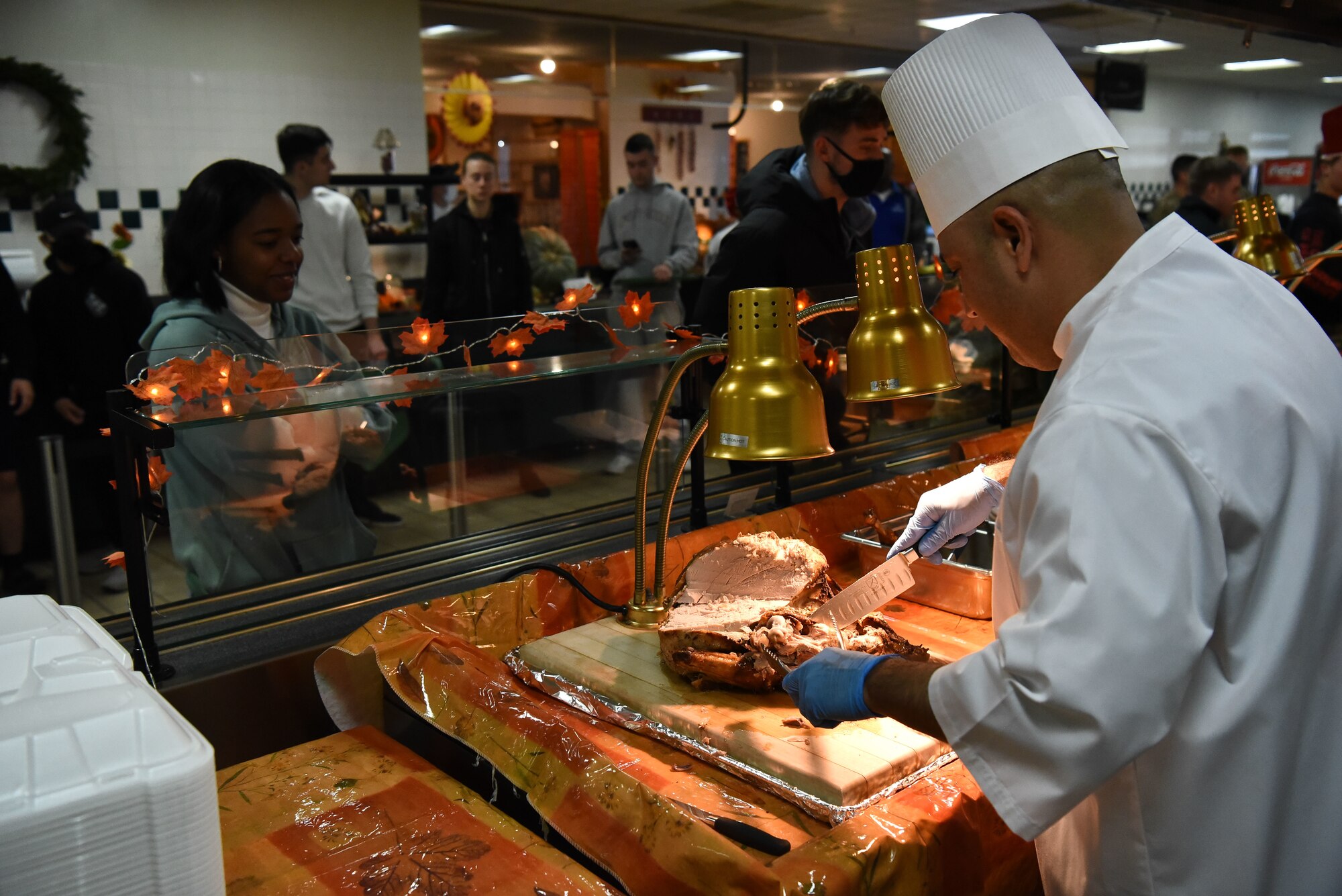 Military member cuts a turkey for a military member.
