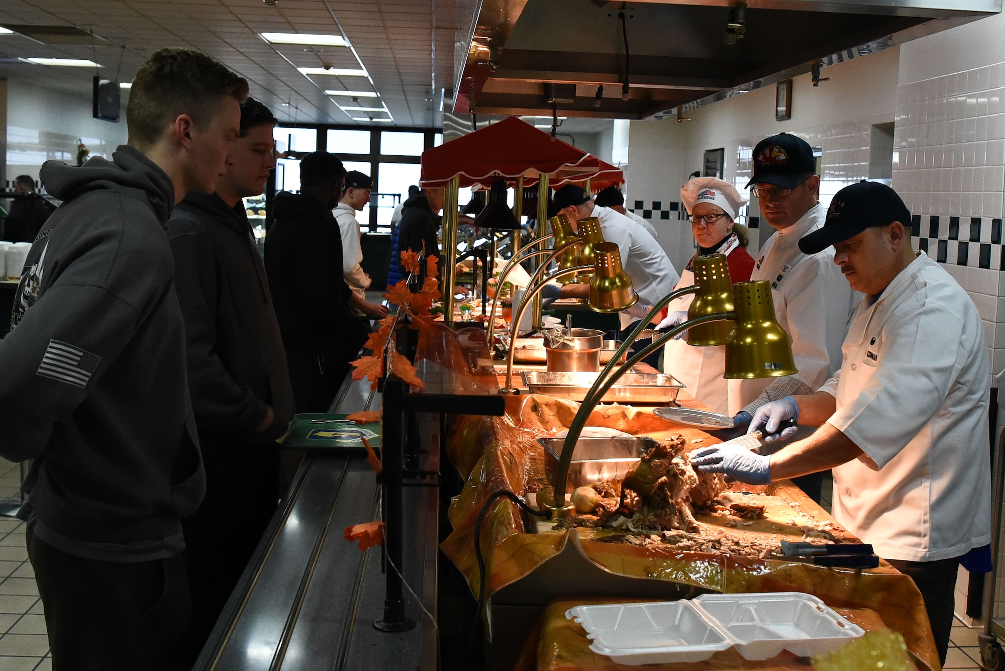 Military members serve food to younger military members.