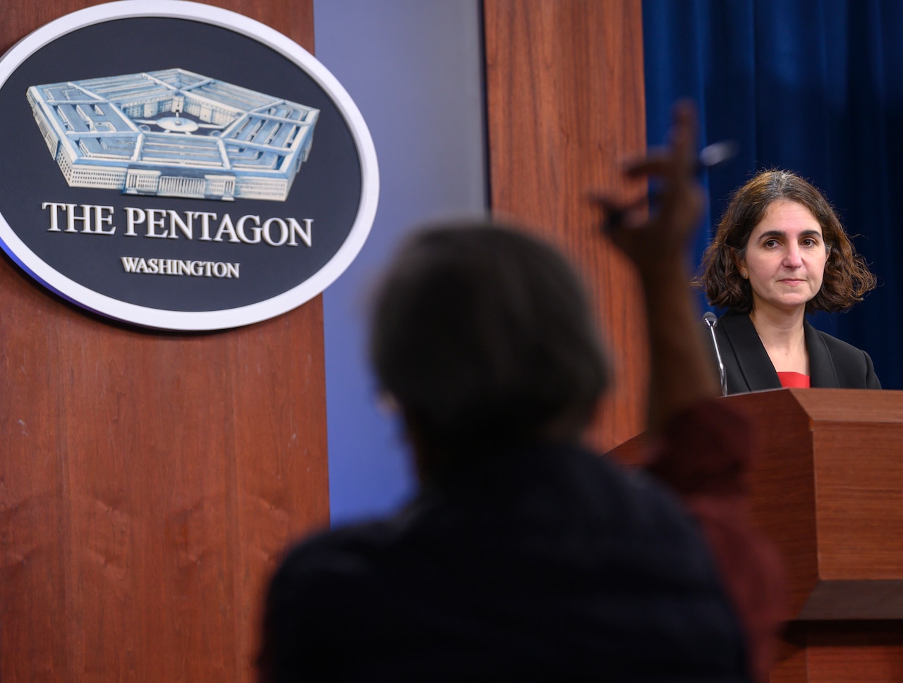 A woman briefs people in a Pentagon studio.