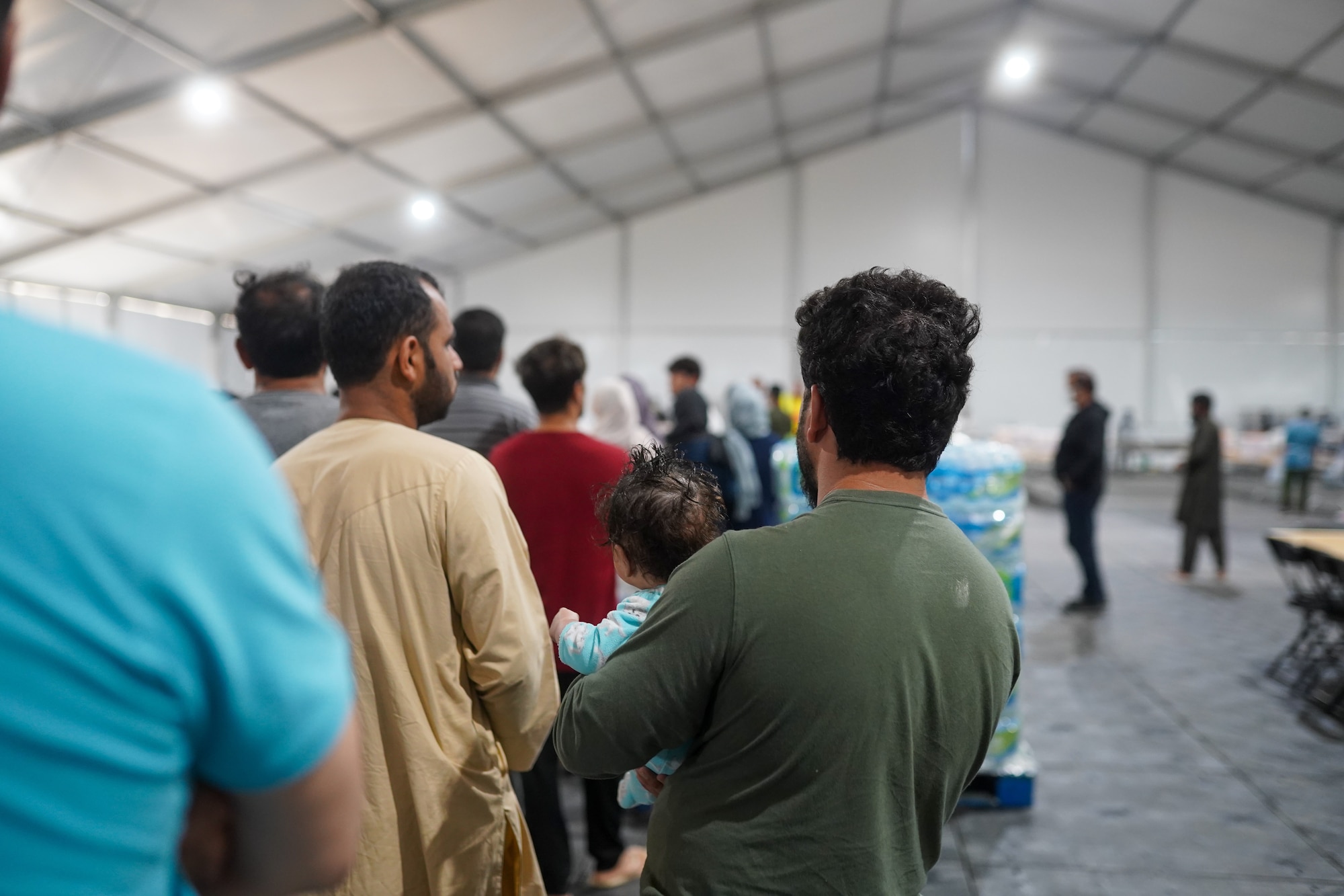 Afghans wait in line to be served food at a newly constructed dining facility in Liberty Village, Joint Base McGuire-Dix-Lakehurst, New Jersey, Sept. 15, 2021. The Department of Defense, through U.S. Northern Command, and in support of the Department of Homeland Security, is providing transportation, temporary housing, medical screening, and general support for at least 50,000 Afghan evacuees at suitable facilities, in permanent or temporary structures, as quickly as possible. This initiative provides Afghan personnel essential support at secure locations outside Afghanistan. (U.S. Air Force photo by 2nd Lt. Taylor Ferry)