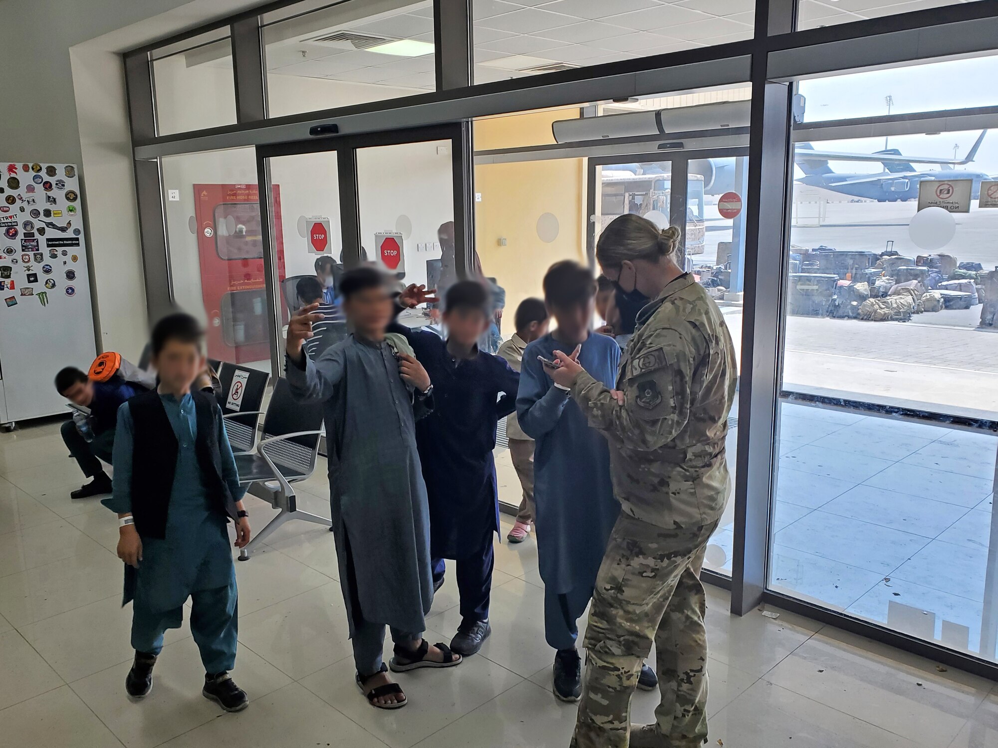 U.S. Air Force Airman 1st Class Cassandra Wesley, a boom operator assigned to the 91st Air Refueling Squadron (ARS) and children from Afghanistan interact in a passenger terminal at Al Udeid Air Base, Qatar, Aug. 26, 2021