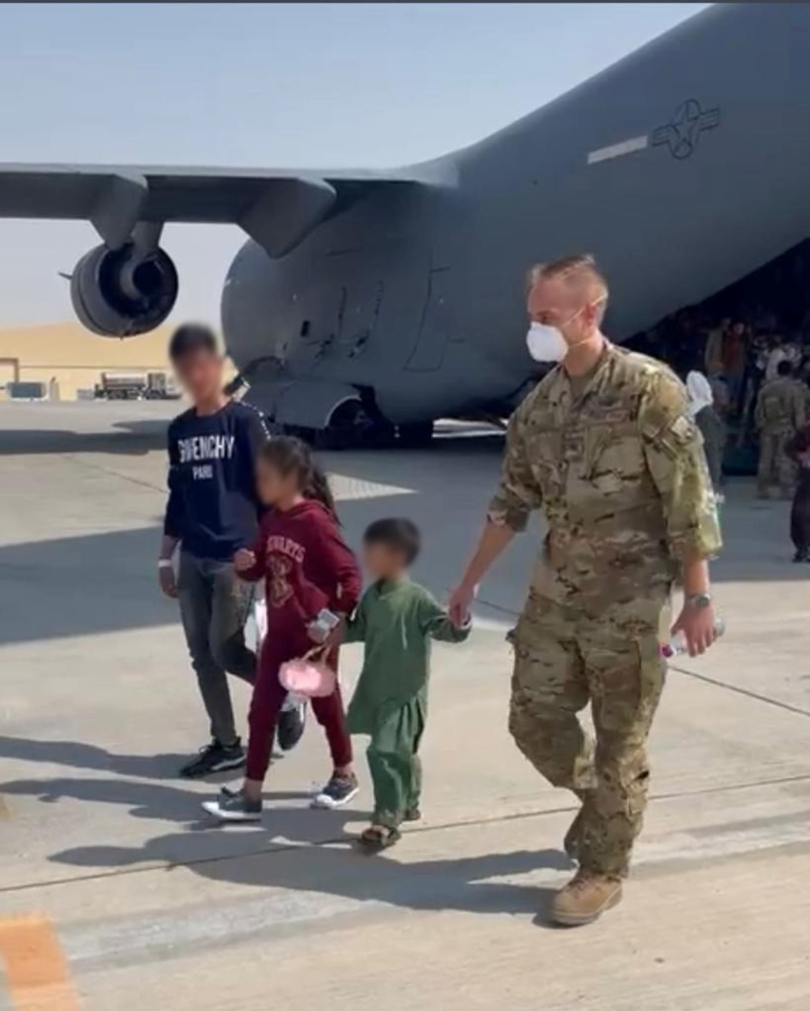 U.S. Air Force Maj. Benjamin Schmidt, a KC-135 Stratotanker evaluator pilot assigned to the 91st Air Refueling Squadron (ARS), walks with children from Afghanistan, Aug. 28, 2021, at Al Udeid Air Base, Qatar.