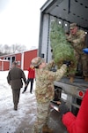 New York Army National Guard Sgt. 1st Class Jason Wells, assigned to the Recruiting and Retention Battalion, passes a tree up to Sgt. Hunter Bates, another volunteer assigned to Bravo Company, 3rd Battalion, 126th Aviation Regiment, as they load 110 donated Christmas Trees at Ellms Tree Farm in Ballston Spa, N.Y., Nov. 29, 2021, for delivery to military bases around the country to support troops and military families this holiday season. More than 15 volunteers from the New York Army and Air National Guard joined Capital District area veterans to help load trees.