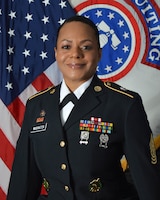 woman in uniform standing in front of two flags.