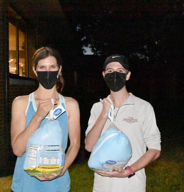Candace Anderson, left, and Garrett Masters display the frozen turkeys they won for being the first female and male runners to cross the finish line during the 36th annual Arnold Engineering Development Complex Turkey Trot, Nov. 10, 2021, at the Arnold Lakeside Complex on Arnold Air Force Base, Tenn. Anderson is the wife of Maj. Wesly Anderson. Masters is the son of Arnold engineer Dr. James Masters. The Turkey Trot drew dozens of members of the AEDC workforce and their families. (U.S. Air Force photo by Bradley Hicks)