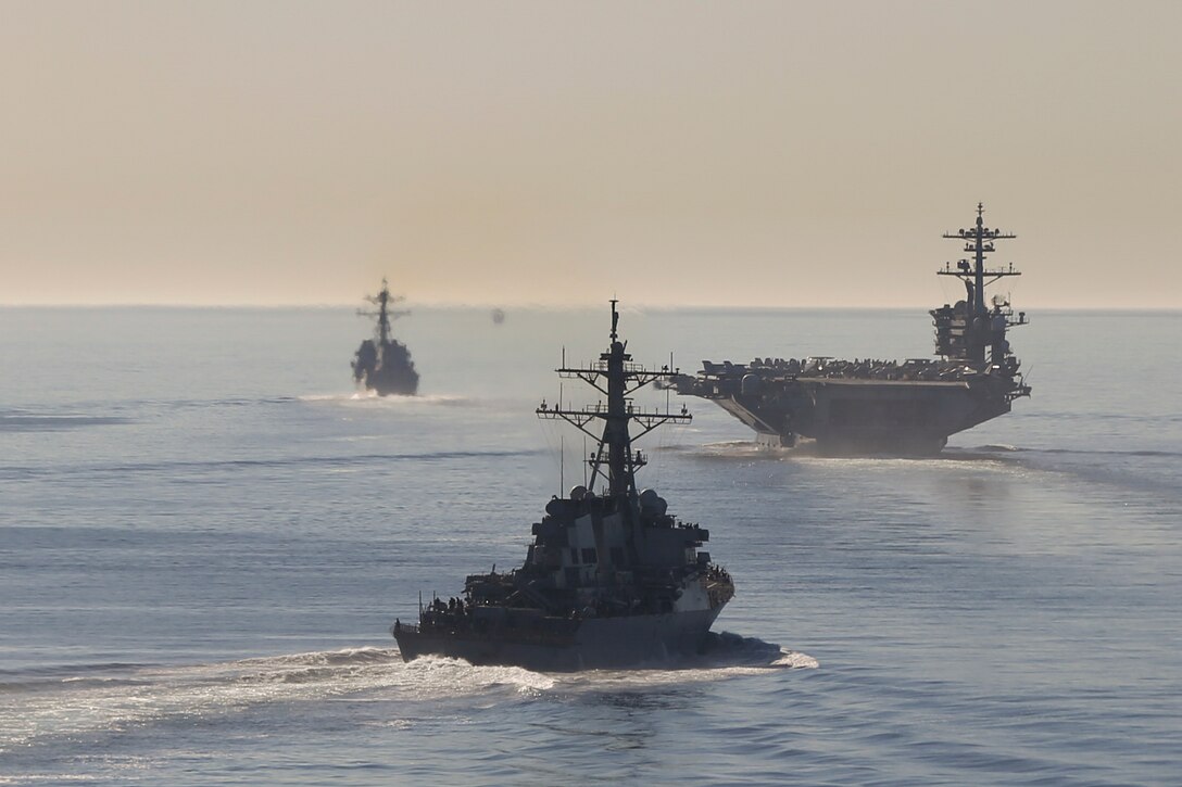 Three ships transit a body of water.