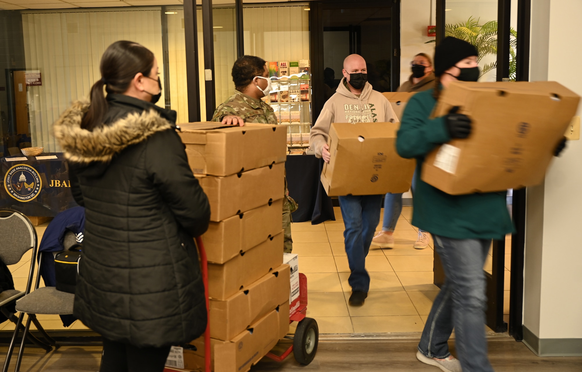 Volunteers deliver food to the chapel at Joint Base Anacostia-Bolling, Washington, D.C., Nov. 19, 2021. A group of more than 50 volunteers made up of U.S. Airmen, Sailors, and base and local community volunteers joined forces to support the chapel and first sergeant association holiday charitable food drive. Volunteers packed bags with frozen chickens and turkeys, pasta, apple cider, fresh vegetables, and canned foods and distributed them to military families on base. (U.S. Air Force photo by Benjamin Matwey)