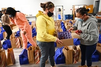 Volunteers fill food bags in the chapel at Joint Base Anacostia-Bolling, Washington, D.C., Nov. 19, 2021. A group of more than 50 volunteers made up of U.S. Airmen, Sailors, and base and local community volunteers joined forces to support the chapel and first sergeant association holiday charitable food drive. Volunteers packed bags with frozen chickens and turkeys, pasta, apple cider, fresh vegetables, and canned foods and distributed them to military families on base. (U.S. Air Force photo by Benjamin Matwey)