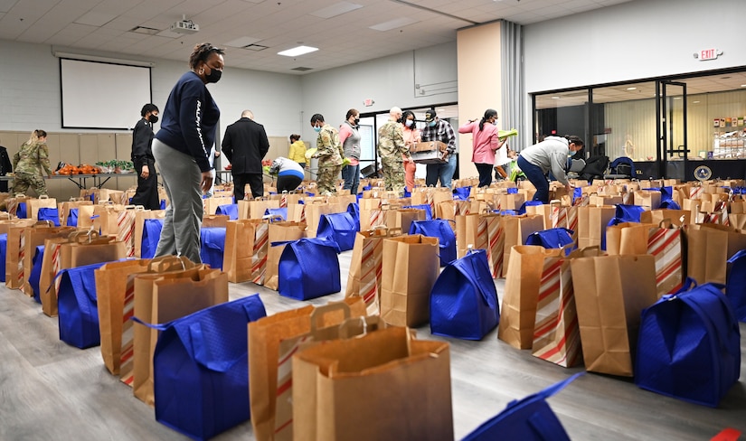 Volunteers fill food bags in the chapel at Joint Base Anacostia-Bolling, Washington, D.C., Nov. 19, 2021. A group of more than 50 volunteers made up of U.S. Airmen, Sailors, and base and local community volunteers joined forces to support the chapel and first sergeant association holiday charitable food drive. Volunteers packed bags with frozen chickens and turkeys, pasta, apple cider, fresh vegetables, and canned foods and distributed them to military families on base. (U.S. Air Force photo by Benjamin Matwey)