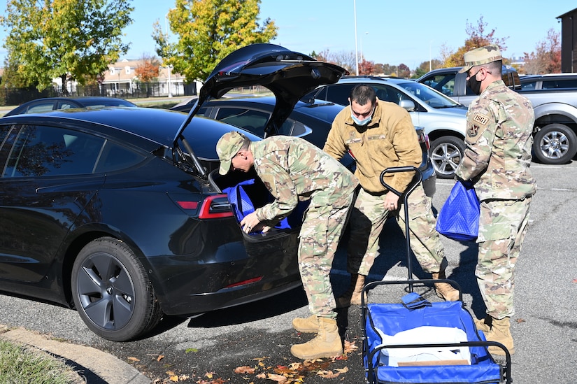 Air Force Chaplain (1st Lt.) Joshua Zarzana, left; Staff Sgt. Ryan Vega, 11th Wing religious affairs Airman; and Senior Master Sgt. Mohammed Abouhashem, United States Honor Guard first sergeant, load food outside the chapel at Joint Base Anacostia-Bolling, Washington, D.C., Nov. 19, 2021. A group of more than 50 volunteers made up of U.S. Airmen, Sailors, and base and local community volunteers joined forces to support the chapel and first sergeant association holiday charitable food drive. Volunteers packed bags with frozen chickens and turkeys, pasta, apple cider, fresh vegetables, and canned foods and distributed them to military families on base. (U.S. Air Force photo by Benjamin Matwey)