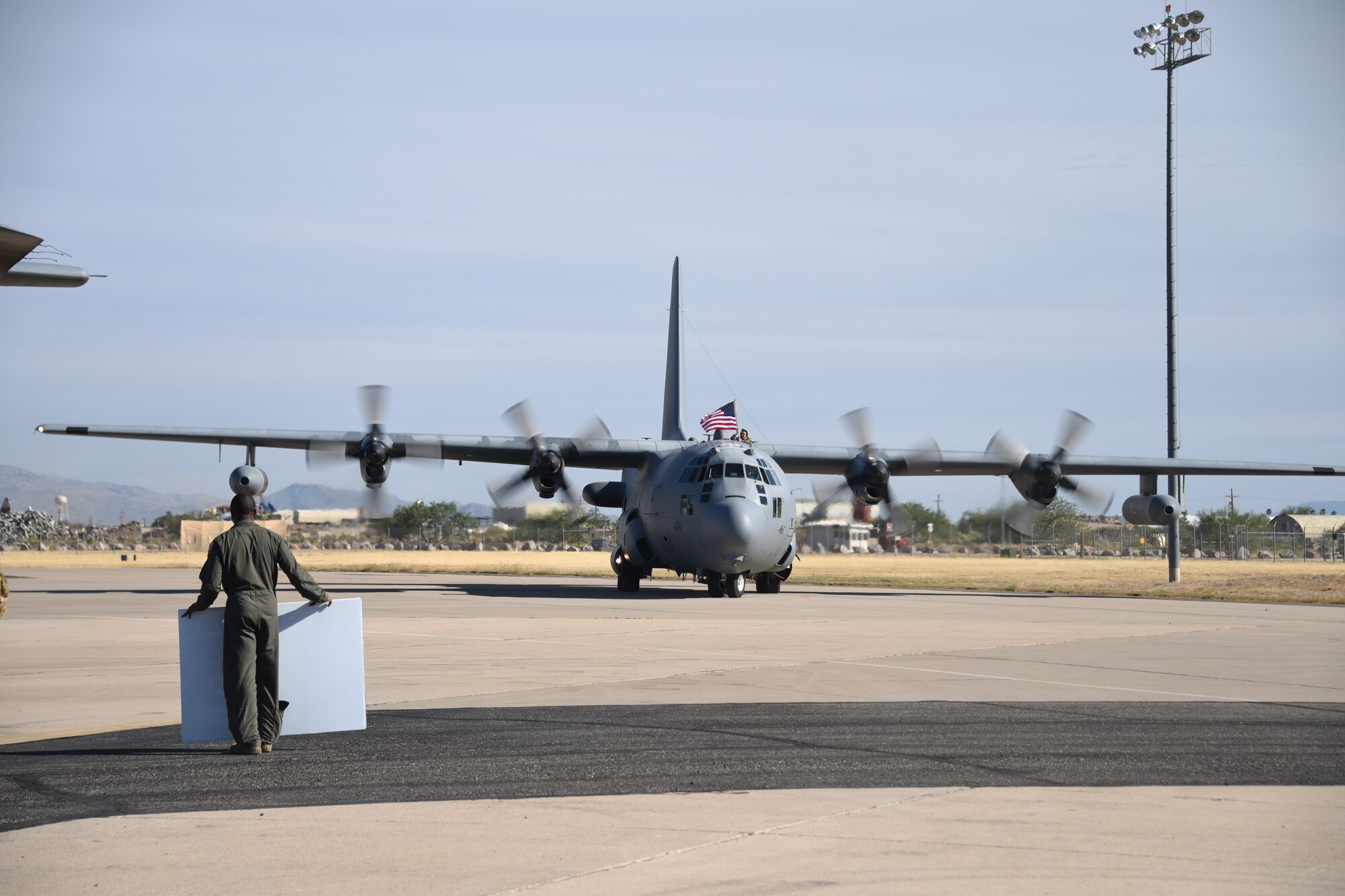 A photo of an Airman waving a flag atop the EC-130H while taxiing.