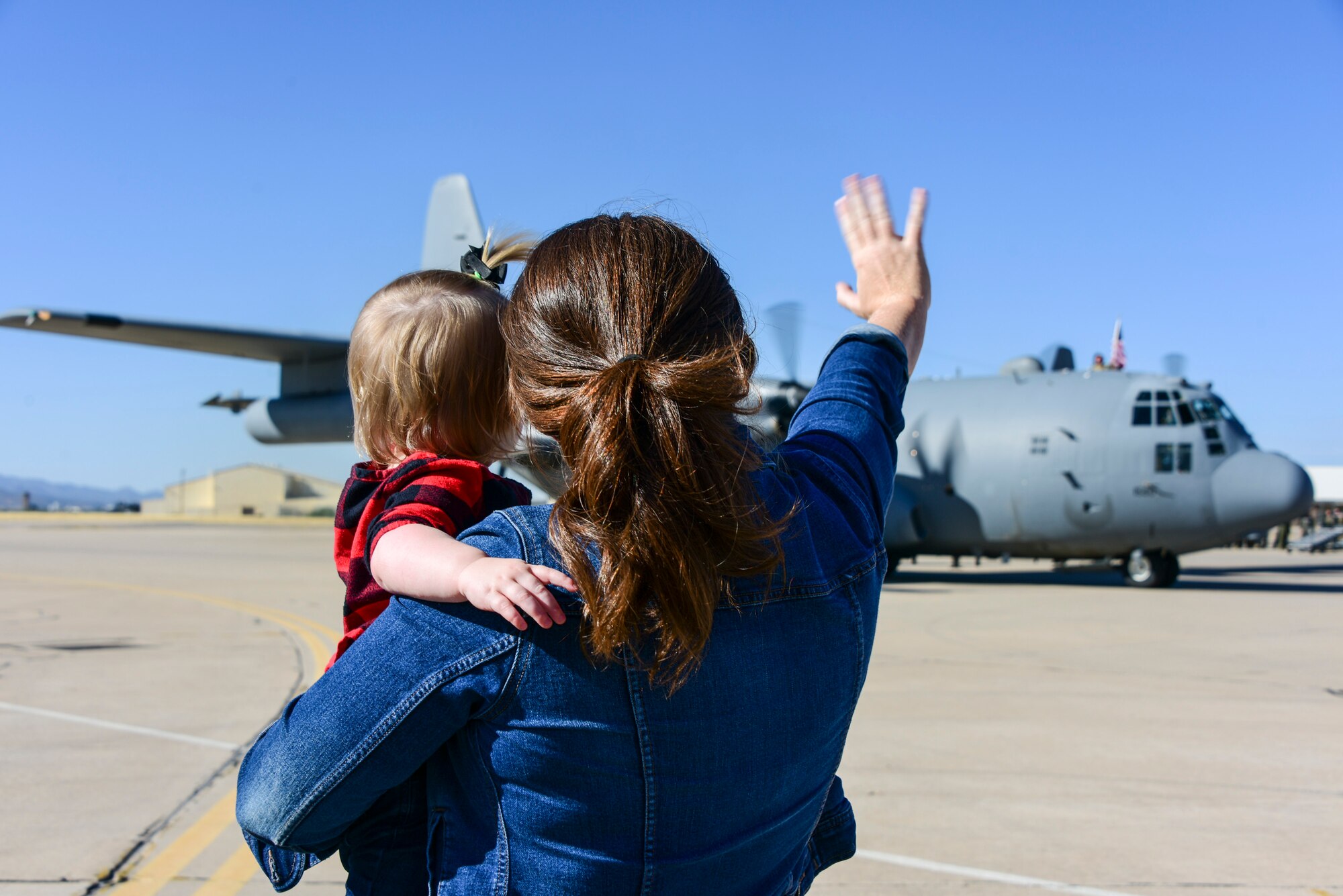 A photo of a woman and her child waving to an EC-130H as it parks.