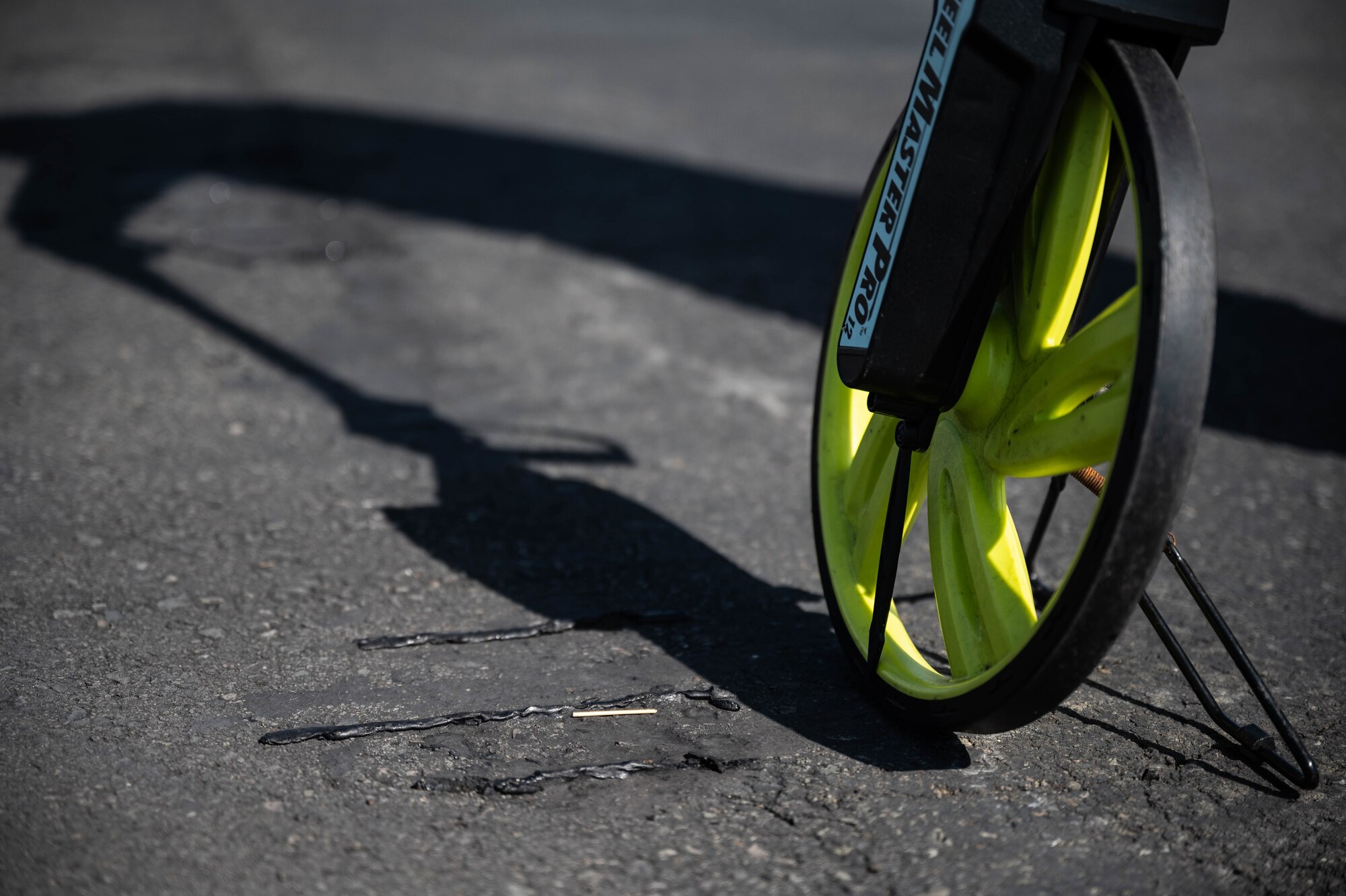 A measuring wheel is placed next to damage on the flightline created by the weight of an aircraft at Joint Base Pearl Harbor-Hickam, Hawaii, Nov. 17, 2021. Airmen assigned to the airfield management flight are responsible for any potential discrepancy on the flightline that could cause aircraft damage or harm personnel. (U.S. photo by Staff Sgt. Alan Ricker)
