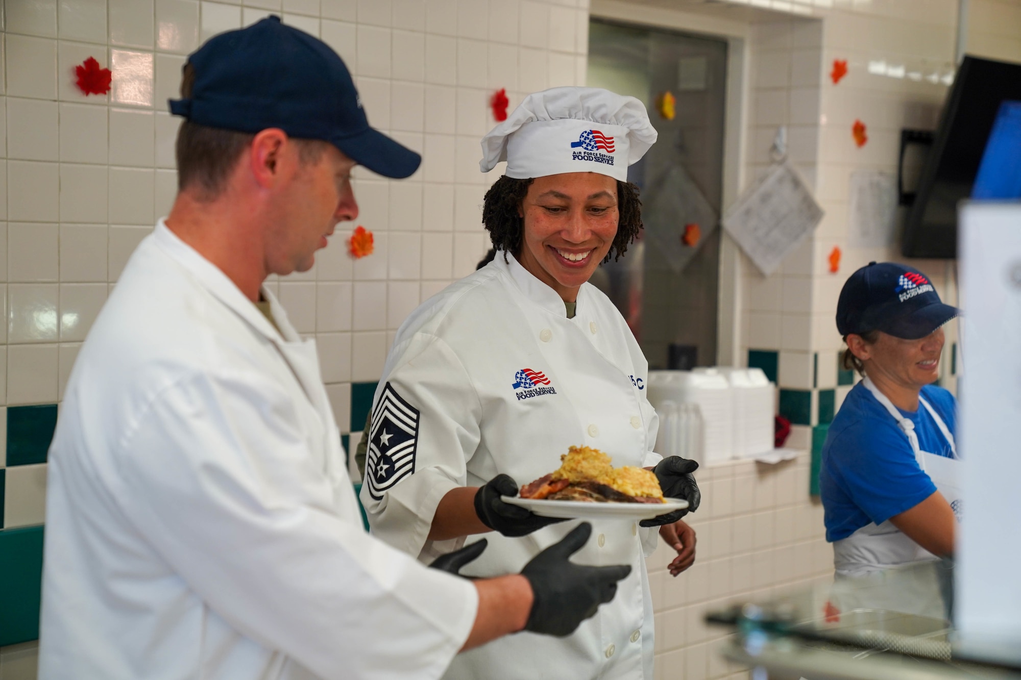 Chief Master Sgt. Sheronne King, 15th Wing command chief and Chief Master Sgt. Christopher Gibson, 15th Medical Group command chief serves airmen lunch at the Hale Aina Dining Facility, November 25, 2021.  Leaders from Joint Base Pearl Harbor-Hickam served airmen and their families lunch on Thanksgiving. (U.S. Air Force photo by Airman 1st Class Makensie Cooper)