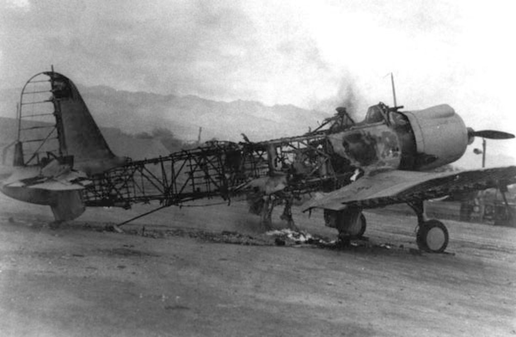 A burned out airplane sits on a runway.