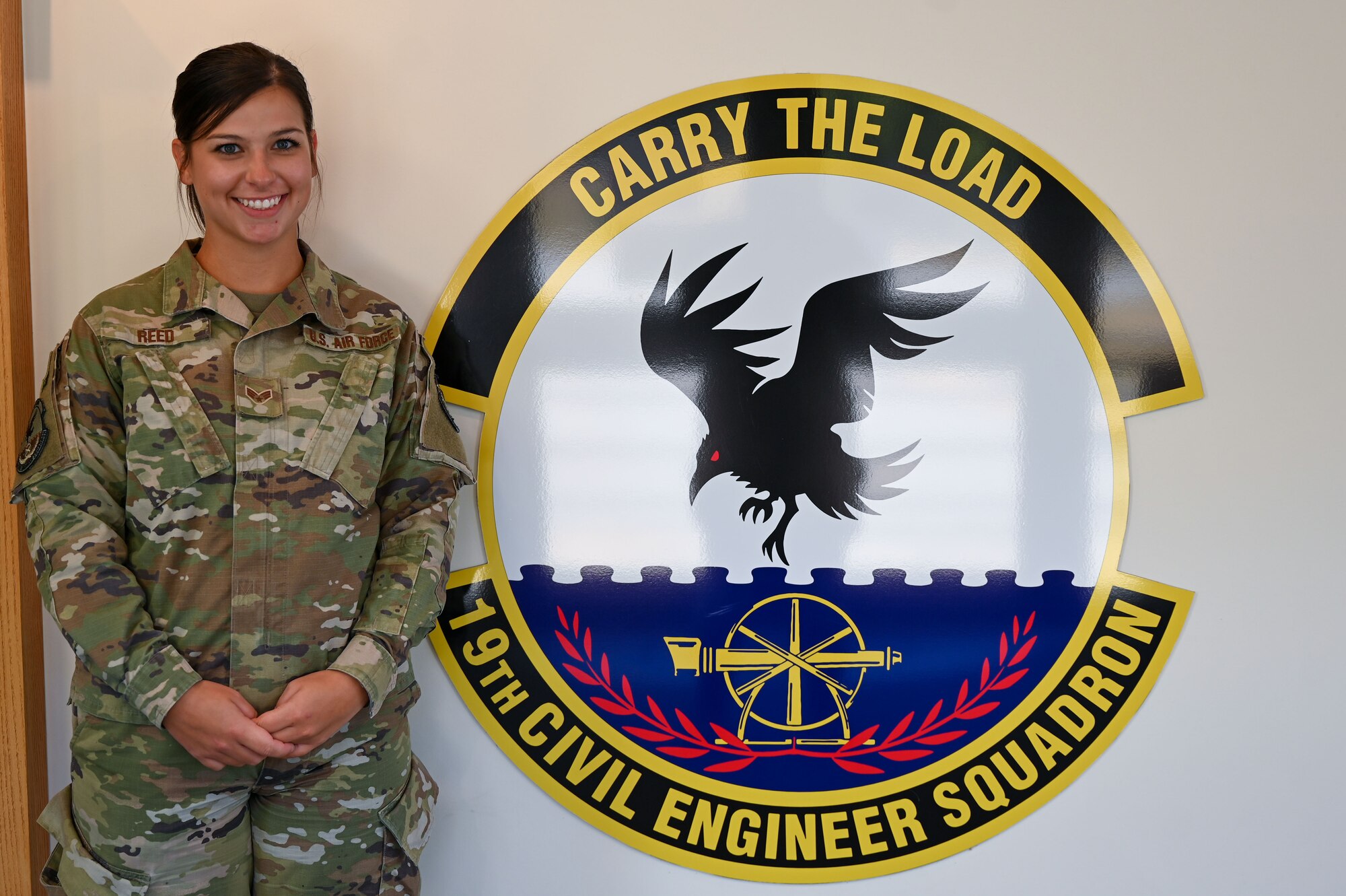 An Airman stands in front of the 19th Civil Engineer Squadron's sign.
