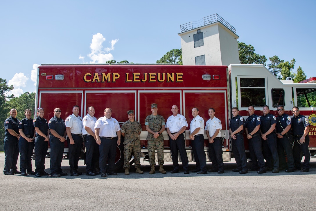 U.S. Marine Corps Brig. Gen. Andrew M. Niebel, center right, commanding general, Marine Corps Installations East-Marine Corps Base Camp Lejeune and Col. Kyle G. Phillips, center left, commanding officer, Headquarters and Support Battalion, Marine Corps Installations East-Marine Corps Base Camp Lejeune stand with the Camp Lejeune Fire and Emergency Services Division, at their Training Ground, on MCB Camp Lejeune, North Carolina, July 9, 2021.