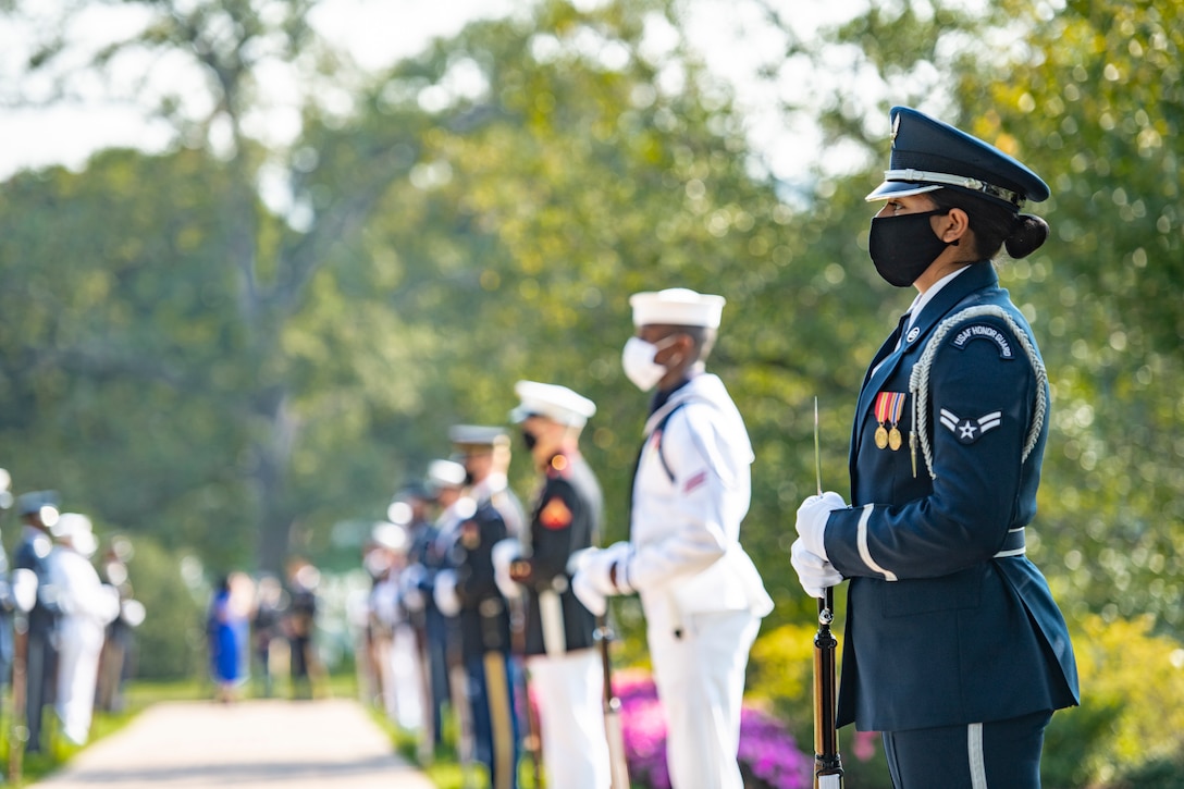 Service members in dress uniform stand at attention.