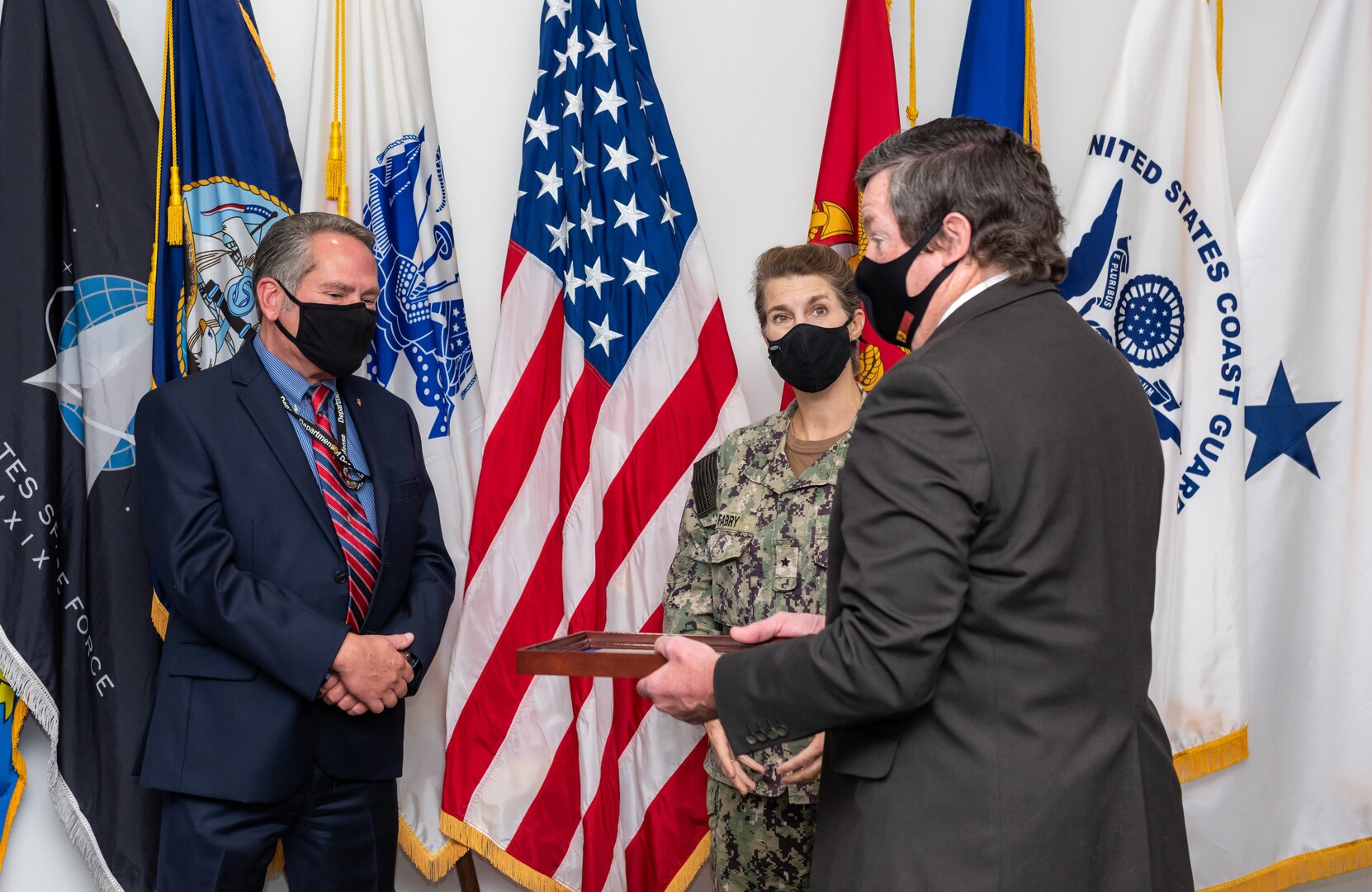 Eddy Poprock, left; Rear Admiral Kristen Fabry, center; Dan Bell, right.