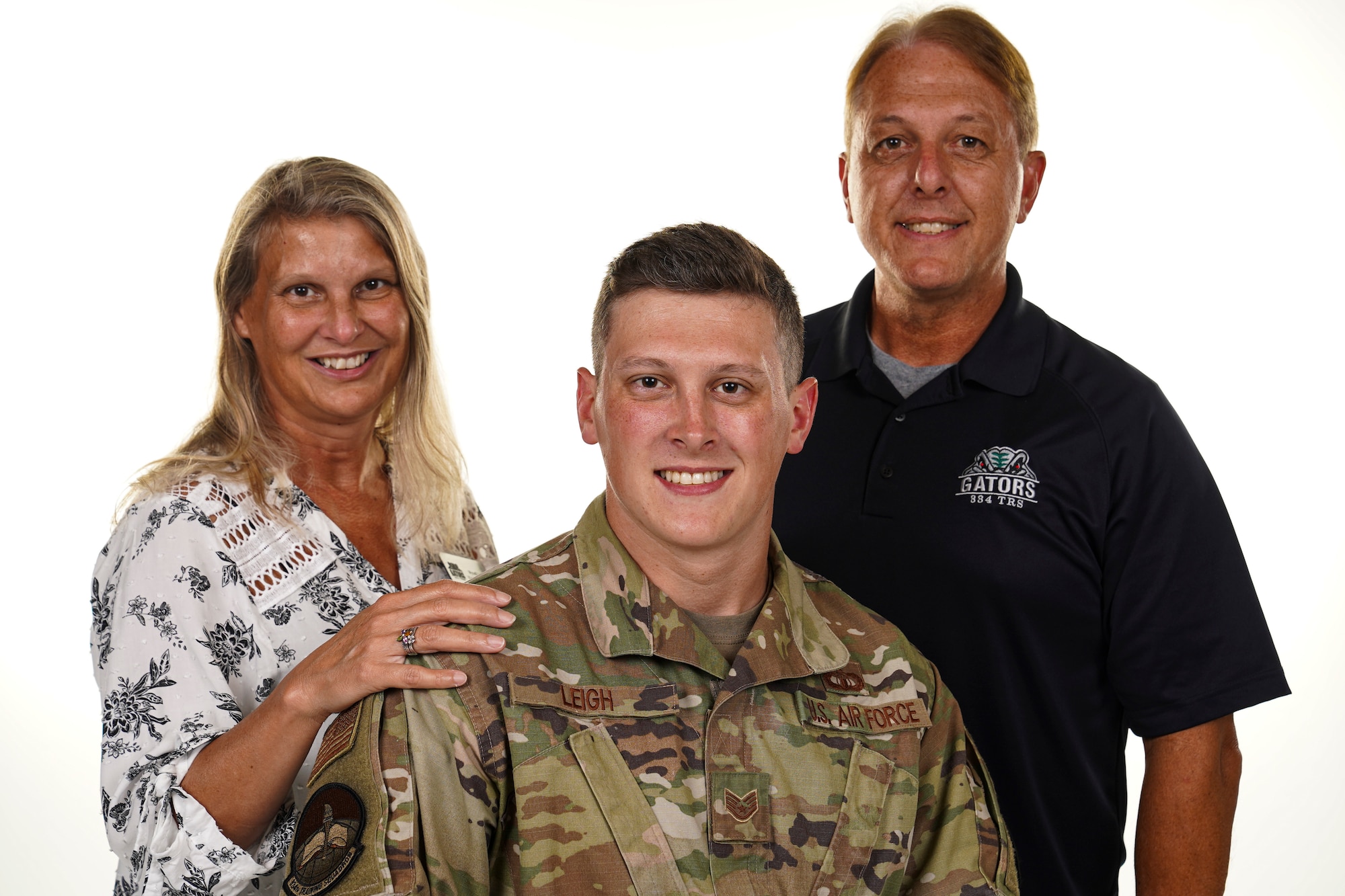 Wynell Leigh, 334th Training Squadron flight secretary, SSgt Justin Leigh, 334th TRS air traffic control instructor and Stanley Leigh, 334th TRS ATC master instructor, pose for a photo inside of Wall Studio at Keesler Air Force Base, Mississippi, Sept. 16, 2021. The Leigh family train Airmen from the 334th TRS side-by-side. (U.S. Air Force photo by Senior Airman Spencer Tobler)