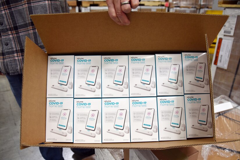 A person holds a box of test kit supplies.