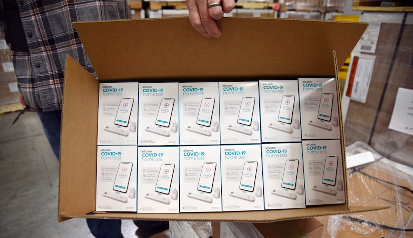 A person holds a box of test kit supplies.