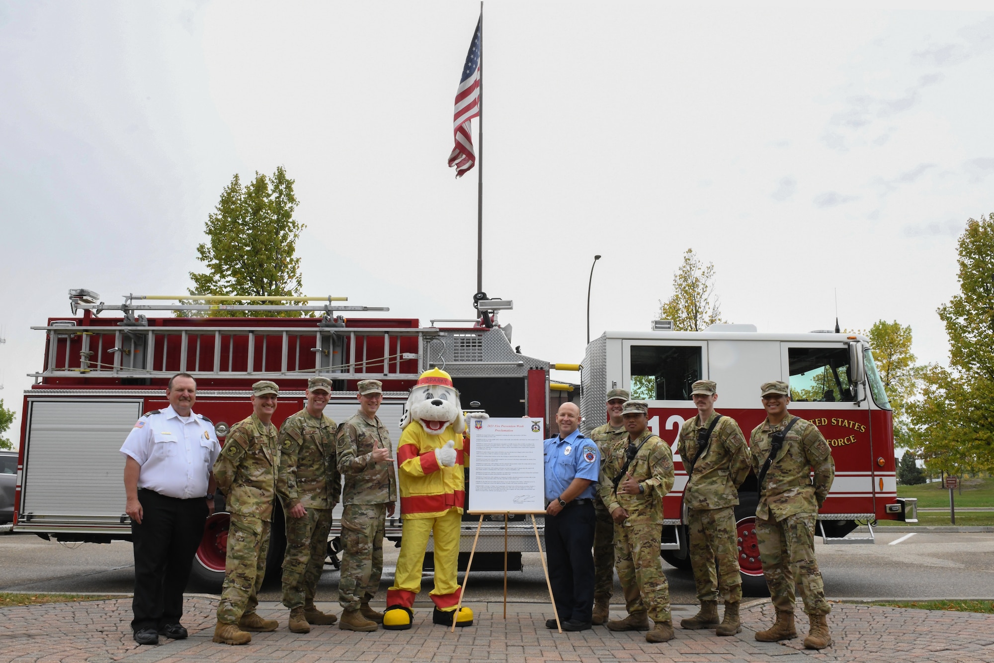 Col. Jeremy Fields, 319th Reconnaissance Wing vice commander, Sparky and members of the 319th Civil Engineer Squadron Fire Department, stand with the 2021 National Fire Prevention Week proclamation on Grand Forks Air Force Base, N.D. Oct. 1, 2021. The fire department on base has set up events throughout the week for GFAFB personnel to participate in. (U.S. Air Force Photo by Airman 1st Class Ashley Richards)