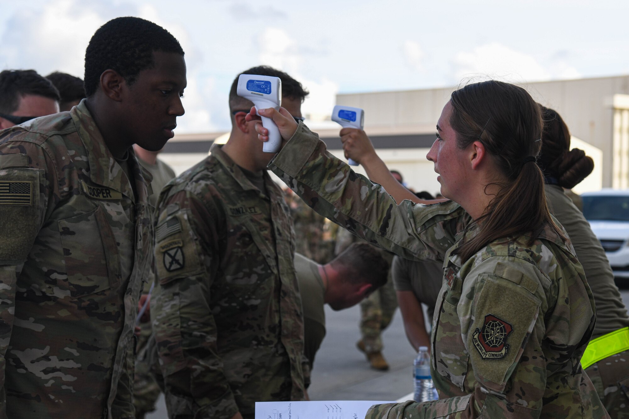 U.S. Air Force Airmen assigned to the 628th Medical Group take temperatures as a part of in-processing for the U.S. Army Soldiers assigned to the 82nd Airborne Division, Pope Army Airfield, N.C., to board a C-17 Globemaster III at Joint Base Charleston, S.C.