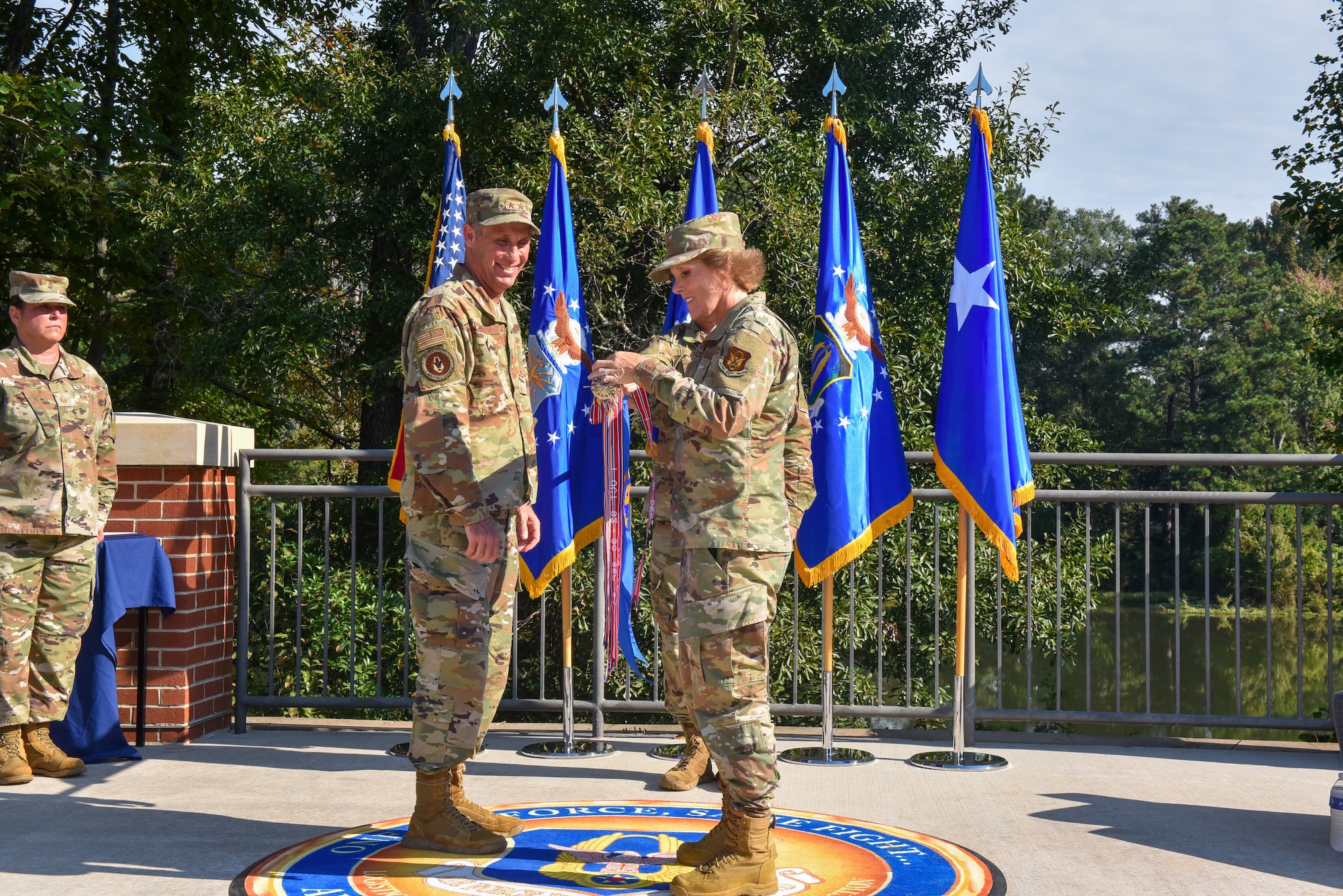 Maj. Gen. Matthew J. Burger, deputy commander of Air Force Reserve Command, left, and Brig. Gen. Stacey L. Scarisbrick, commander of AFRC Force Generation Center, place the Air Force Organizational Excellence award streamer to the guidon during a ceremony celebrating the 10th anniversary of AFRC's FGC at Robins Air Force Base, Georgia, Oct. 1, 2021. The FGC is the single organization responsible for generating Air Force Reserve forces by leveraging Reserve strategic capability to meet operational needs in support of the global force. The Reserve Citizen Airmen who support the FGC perform all aspects of force generation to include oversight, visibility and accountability of more than 70,000 Air Force Reserve forces. (U.S. Air Force photo by Misuzu Allen)