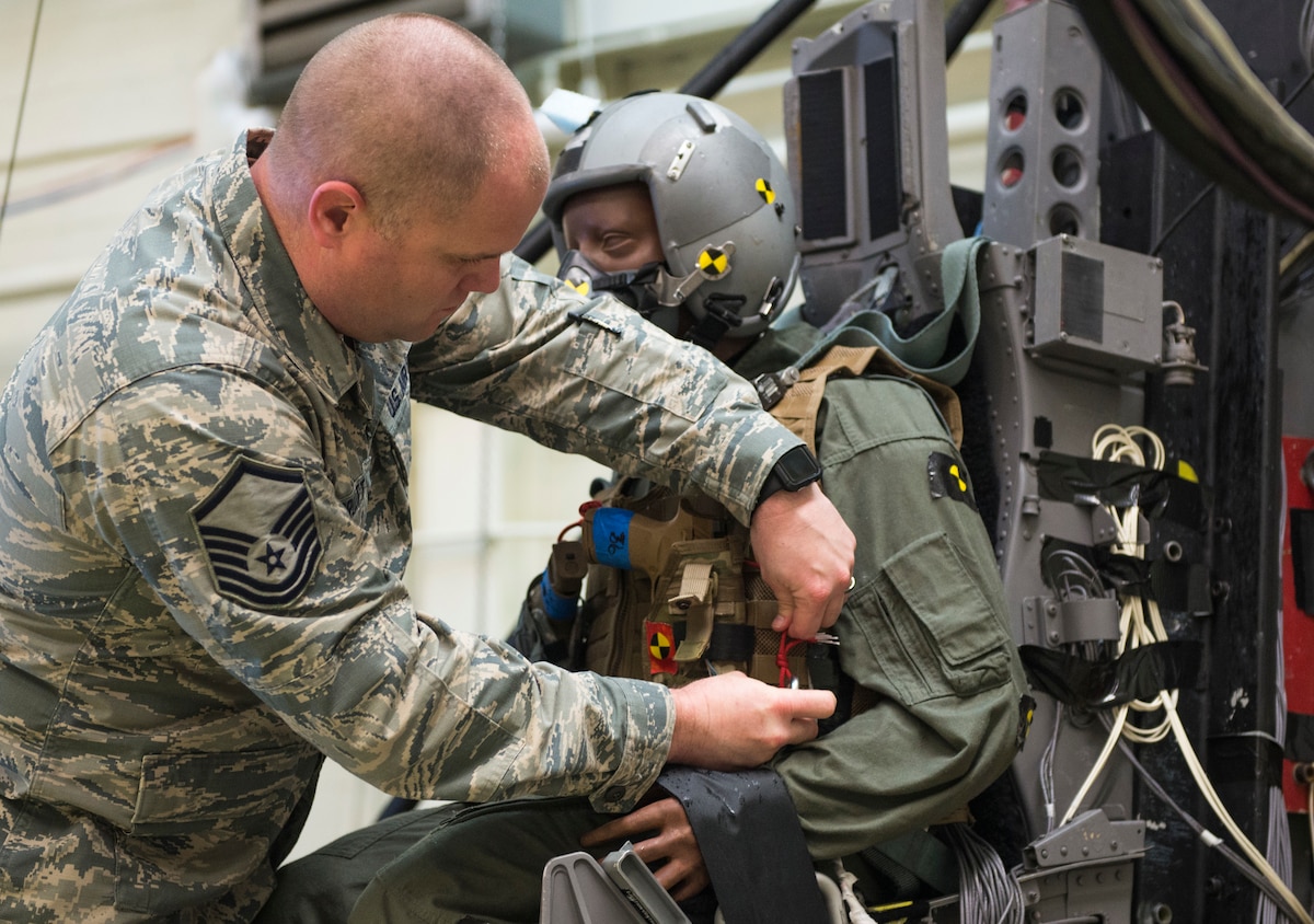 U.S. Air Force Master Sgt. Samuel Pruett, Air Force Operational Test and Evaluation Center force protection program manager, based at Eglin AFB, Fla., secures weapons on a test dummy prior to a test of the modular handgun system at Wright-Patterson Air Force Base, Ohio, Dec. 6, 2017. The test address the new modular handgun system’ capability to resist damage during ejection and still function as designed after sustaining ejection forces.  This is the first time any service has conducted this type of demonstration to ensure a side arm is safe for aircrew to carry in ejection seat aircraft. (U.S. Air Force photo by Wesley Farnsworth)