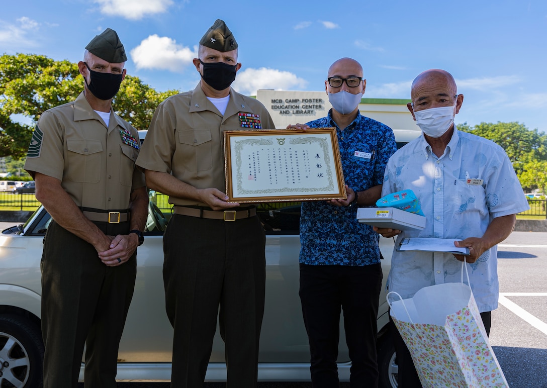 沖縄県北谷町役場の職員から表彰状を授与される米海兵隊基地キャンプ・フォスター基地司令官のジェフリー・ハモンド大佐（左から２番目）