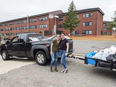 Senior Airman Katlyn Legerstee, left, and Tech. Sgt. Cassandra Dowling, right, both of the 157th Air Refueling Wing, stand in front of the pickup truck and trailer they loaded with clothing donated for vulnerable Afghans temporarily living at Joint Base McGuire-Dix-Lakehurst, Sept. 17, 2021.