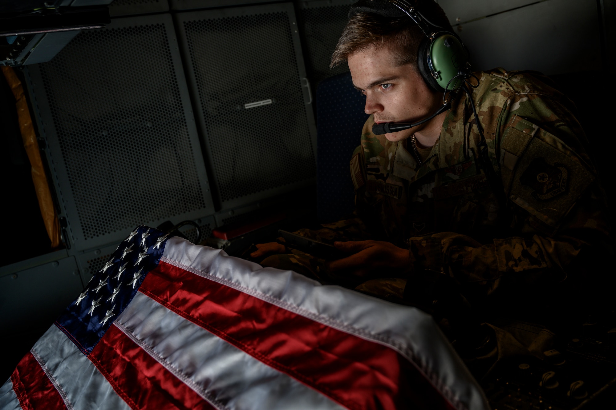 boom operator with American flag, preparing to refuel a jet at night