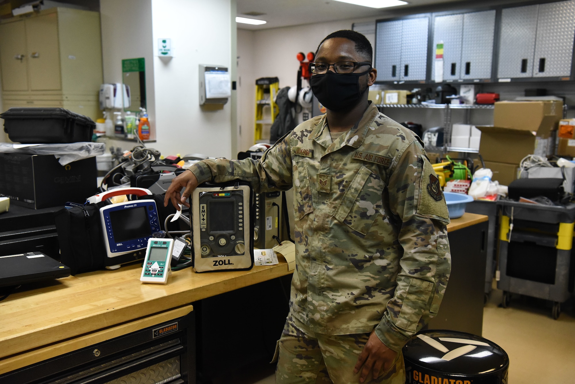 A military member stands next to a oxygen purity tester in his office
