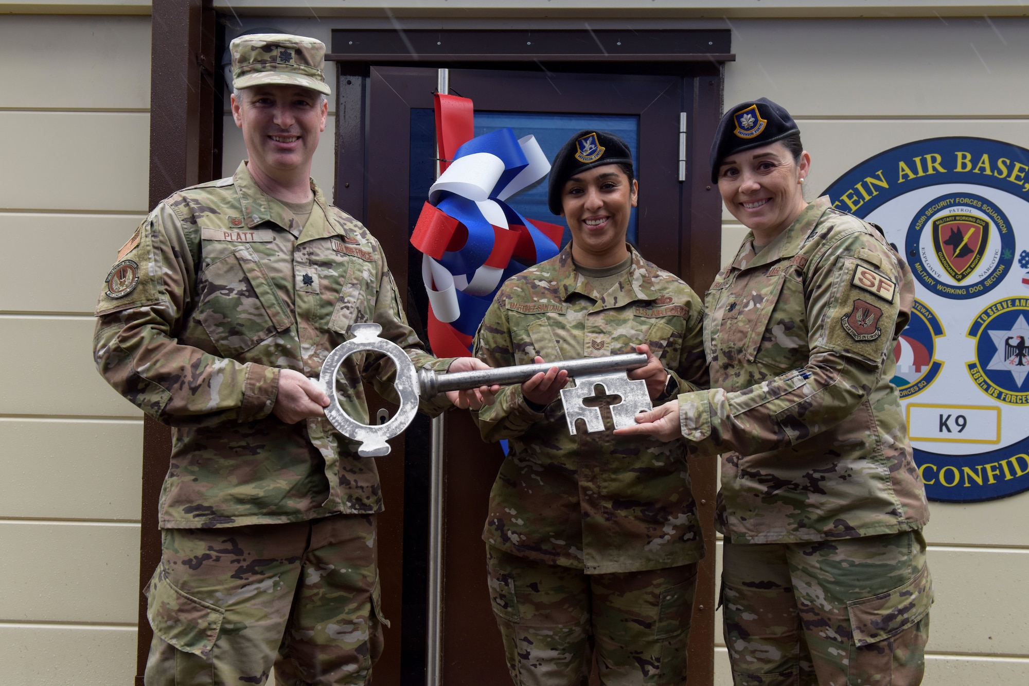 U.S. Air Force Lt. Col. Seth Platt gives Tech. Sgt. Jessica Martinez-Santana and Lt. Col. Cassandra Bates the key to the newly renovated military working dog kennel.