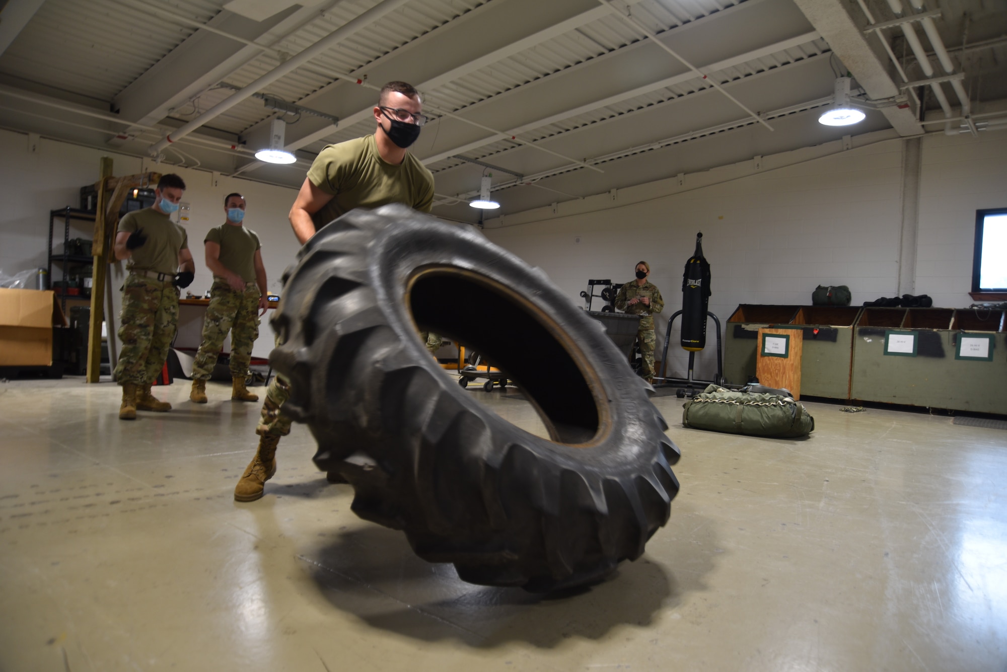 Staff Sgt. Nicholas Willig, 41st Aerial Port Squadron air transportation craftsman, participates in the "fit to fight" portion of the Port Dawg Challenge at Keesler Air Force Base, Miss., Oct. 2, 2021. This part of the fitness portion has Willig raising a heavy tire tread up to pitch it over multiple times as his teammates and evaluators observe. (U.S. Air Force photo by Tech. Sgt. Michael Farrar)