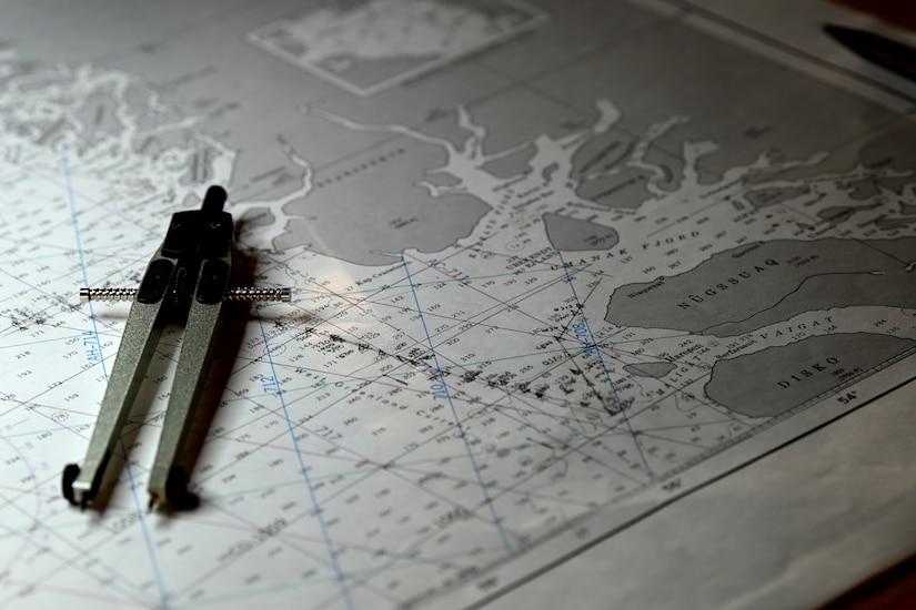 A navigational tool lies across a large map.
