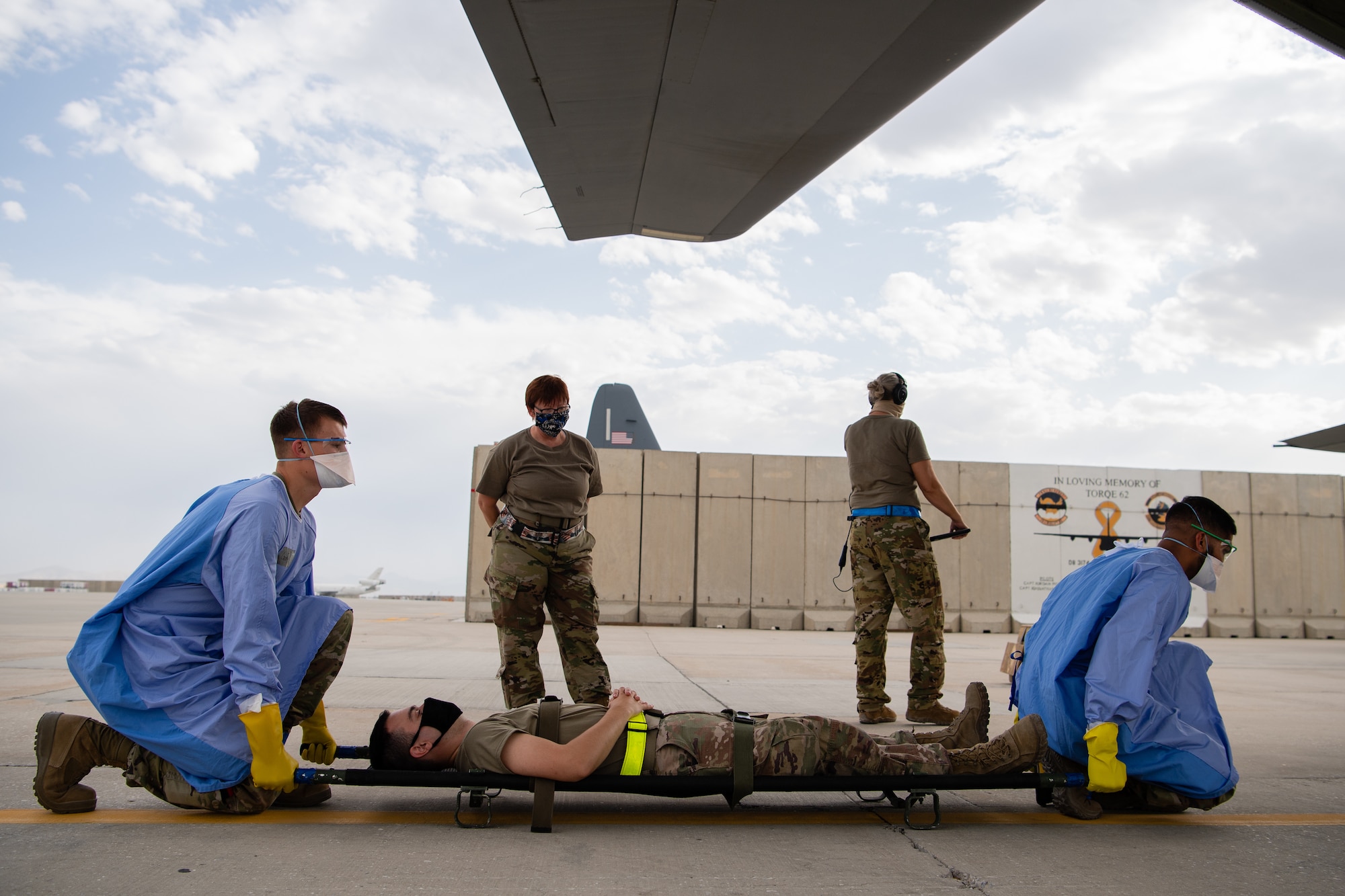 U.S. Air Force members assigned to the 405th Expeditionary Aeromedical Evacuation Squadron lift a litter for transport during a training exercise for the Negatively Pressurized Conex-Lite in Southwest Asia, July 30, 2020.  The NPC-Lite is the latest isolated containment chamber developed for intra-theater airlift of individuals with infectious diseases like COVID-19 and is designed to fit inside a C-130 aircraft.  (U.S. Air Force photo by Staff Sgt. Justin Parsons)