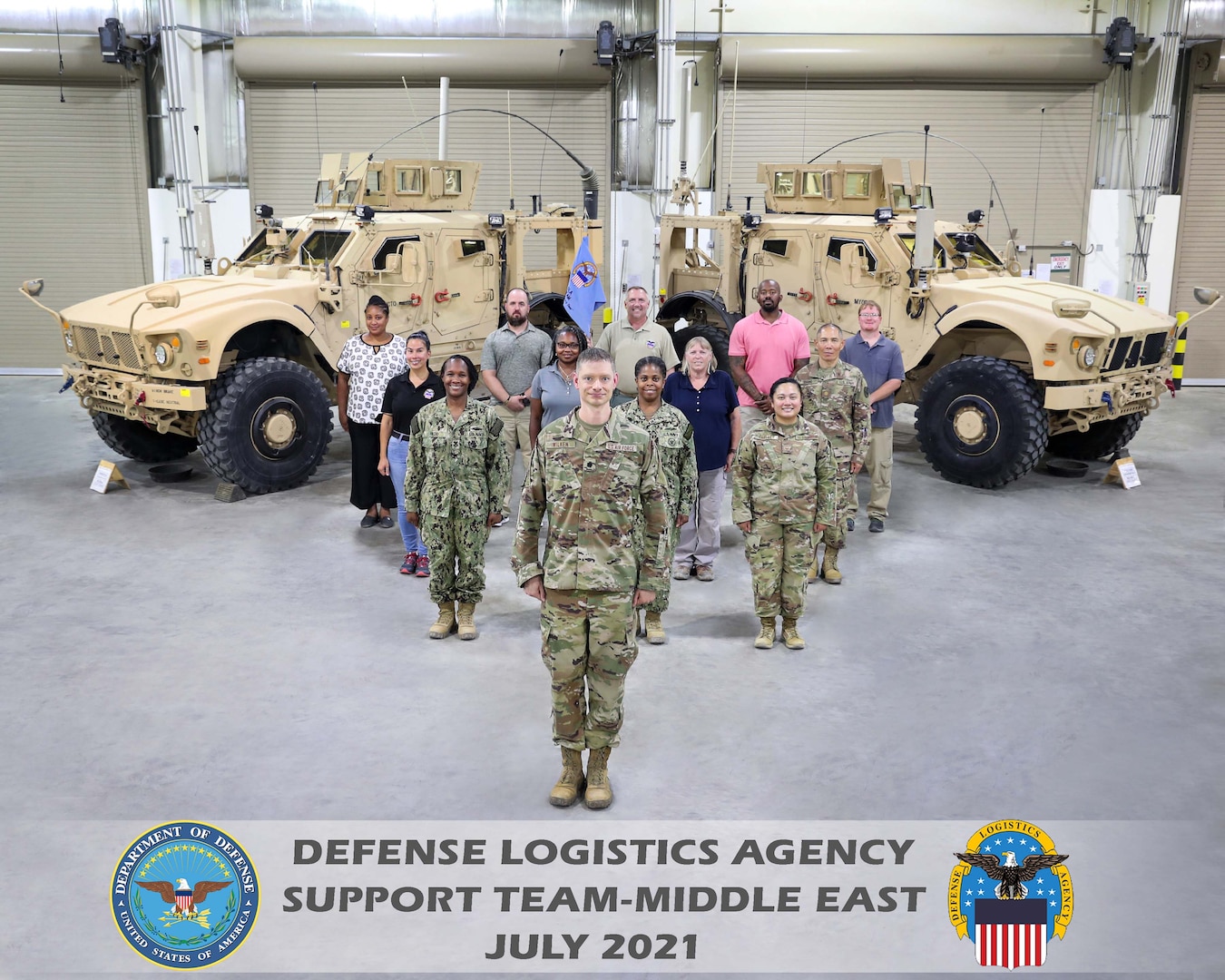 Men and women from DST-ME pose in front of military vehicles.
