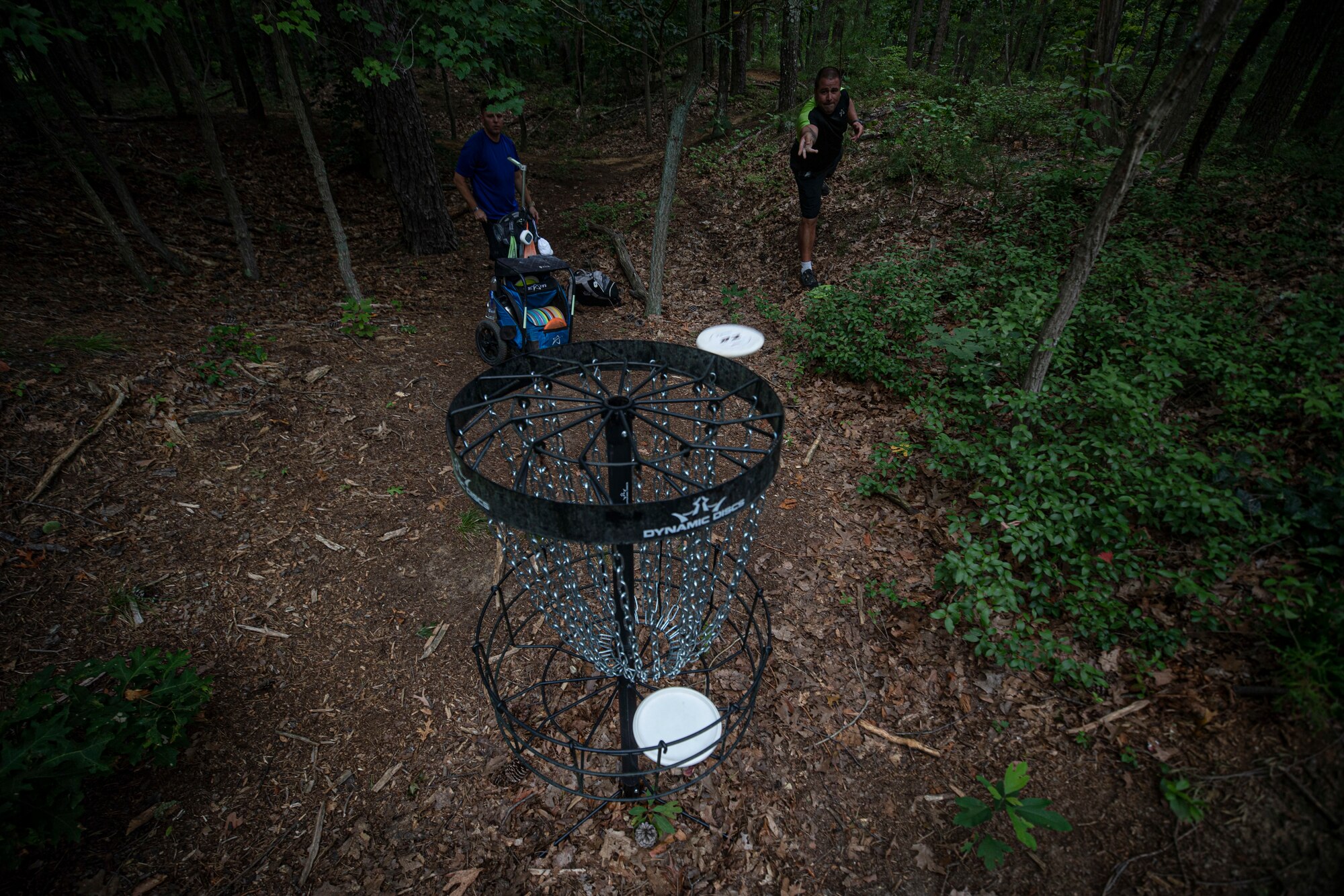 U.S. Air Force Senior Master Sgt. Jeffery Pitcher, right, and Tech. Sgt. Andrew Finger finish up a disc golf hole at the Laurel Pond Disc Golf Course on Joint Base McGuire-Dix-Lakehurst, N.J., Aug. 16, 2021.