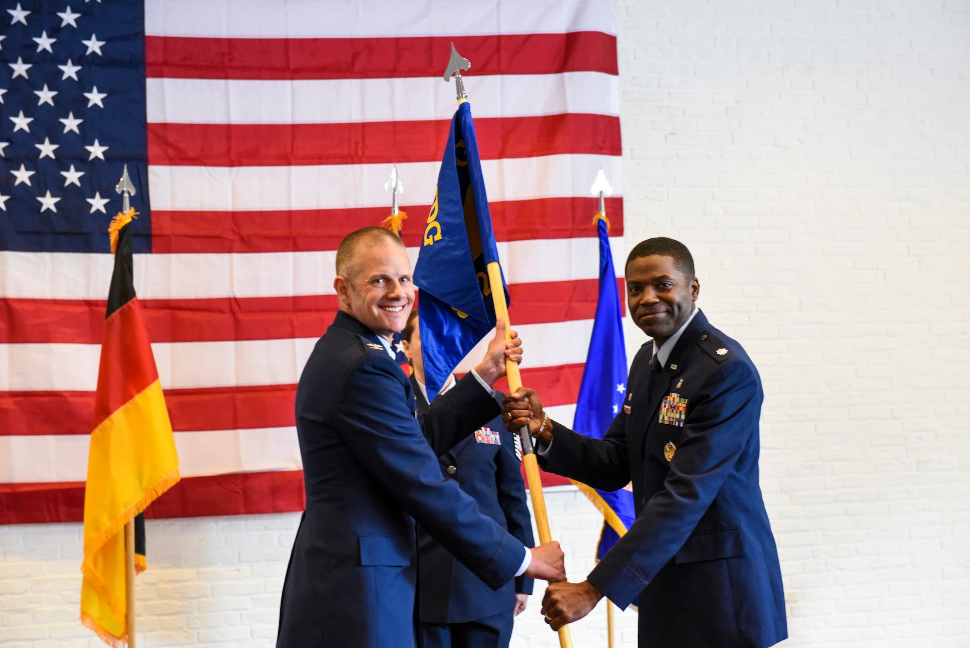 U.S. Air Force Col. Peter French, 52nd Medical Group commander, passes the 52 MDG guidon to U.S. Air Force Lt. Col. Philip Pope, the incoming 852nd Medical Squadron commander, during the 852nd MDS activation ceremony at Geilenkirchen NATO Air Base, Germany, Oct. 1, 2021.