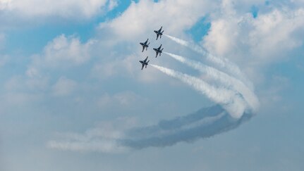 Four military jets perform a bank right turn.