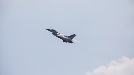 Military jet ascends to the left with contrails appearing from both sides of the aircraft