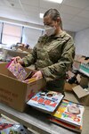 New York Air National Guard Staff Sgt. Scarlett Yates, assigned to the 106th Air Rescue Wing, sorts through donated books for Afghan children at the temporary medical isolation dormitory at Liberty Village, Joint Base McGuire-Dix-Lakehurst, New Jersey, Sept. 27, 2021.  Yates helped deliver an Afghan baby at the base Sept. 7.