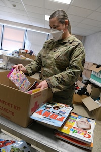 New York Air National Guard Staff Sgt. Scarlett Yates, assigned to the 106th Air Rescue Wing, sorts through donated books for Afghan children at the temporary medical isolation dormitory at Liberty Village, Joint Base McGuire-Dix-Lakehurst, New Jersey, Sept. 27, 2021.  Yates helped deliver an Afghan baby at the base Sept. 7.