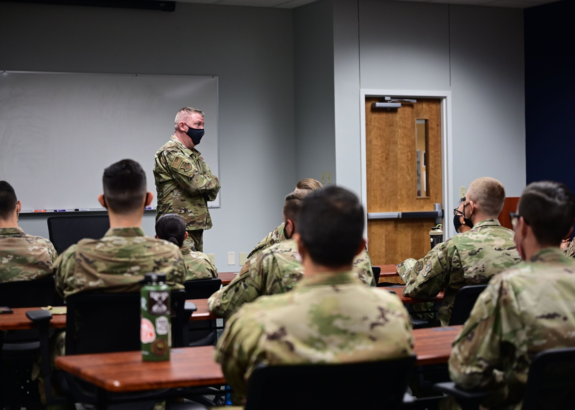 A man gives a speech to a group of Airmen