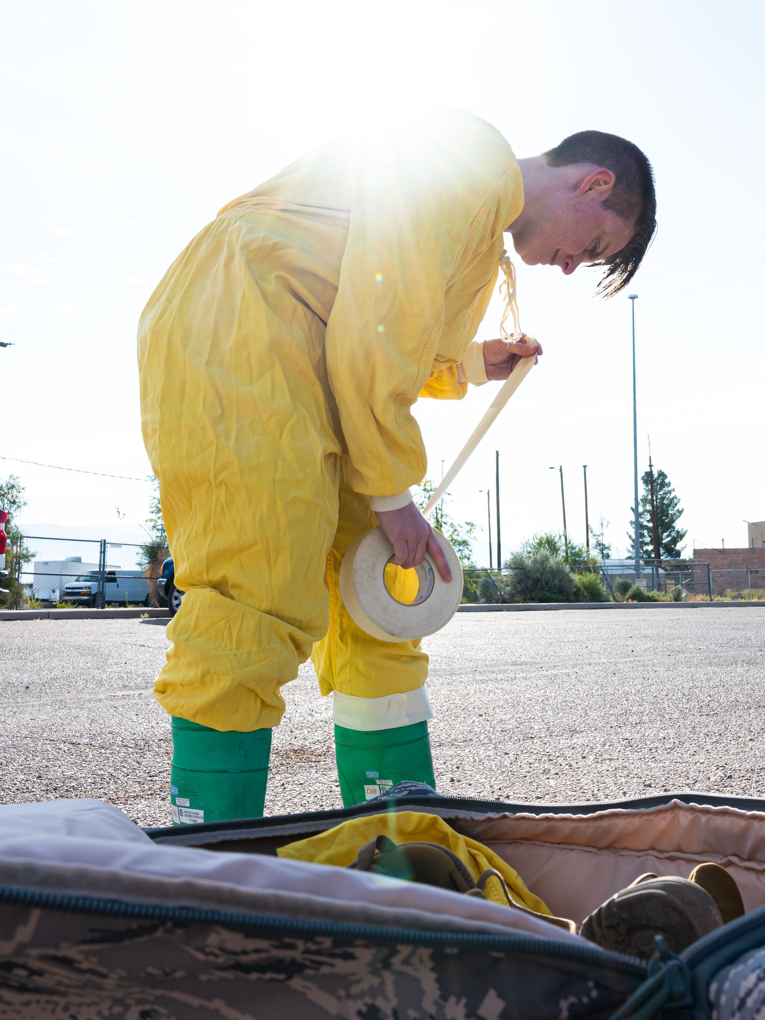 Tech. Sgt. Lisa Sandahl, 49th Civil Engineer Squadron emergency management noncommissioned officer in charge, tears a piece of masking tape during a radiological survey exercise Oct. 1, 2021 on Holloman Air Force Base, New Mexico. The anticontamination suits are sealed tightly with masking tape to prevent radiological particulates from penetrating the seal. (U.S. Air Force photo by Tech. Sgt. BreeAnn Sachs)