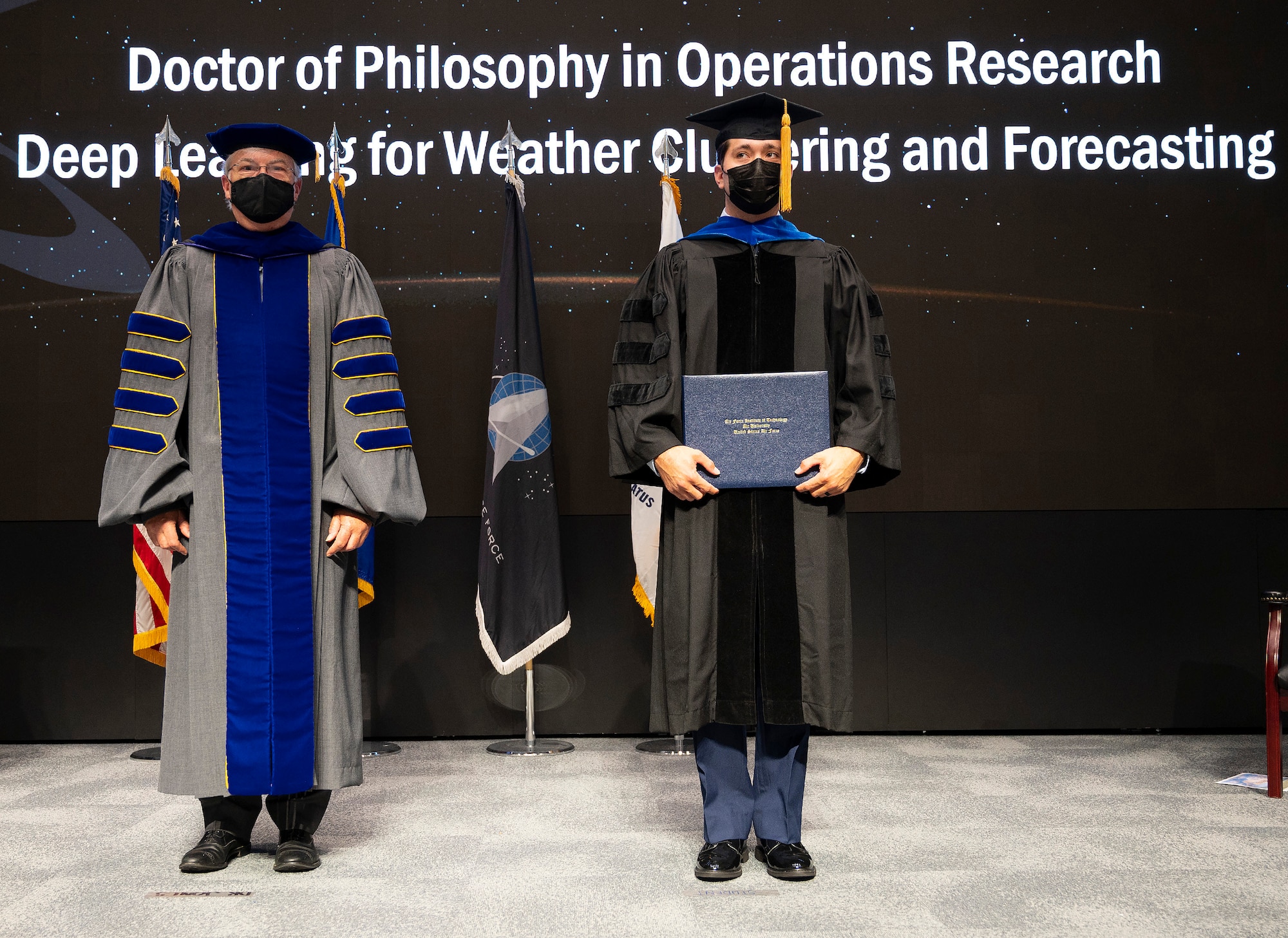 During a graduation ceremony on Sept. 16, 2021, Dr. Walter Jones, director and chancellor of the Air Force Institute of Technology, stands with Capt. Nathanael Beveridge as he receives his Doctor of Philosophy diploma in operations research. (U.S. Air Force photo by R.J. Oriez)