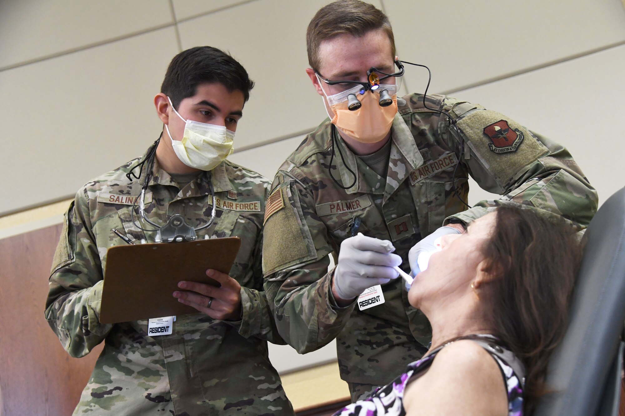 U.S. Air Force Capts. Giany Salinas and Sean Palmer, 81st Dental Squadron dental residents, provide a dental exam on Mary Patano, wife of retired Master Sgt. Nick Patano, during the 10th Annual 81st Medical Group Health Expo inside the Bay Breeze Event Center at Keesler Air Force Base, Mississippi, October 1, 2021. The 81st MDG hosted the walk-in event which included information booths and scheduling appointments for multiple types of cancer and chronic diseases in honor of Breast Cancer Awareness Month. (U.S. Air Force photo by Kemberly Groue)